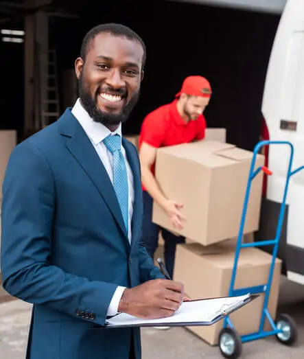 Lächelnder Logistikmanager mit Klemmbrett vor Lieferwagen