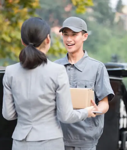 Lächelnder Kurier übergibt ein Paket an eine Geschäftsfrau im Freien